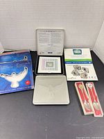 full lot showing two blue boxed stamp sets, two silver tins, Olympic pin card, two packaged spoons