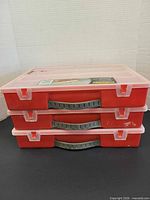 Three stacked red plastic organizers with grey handles