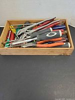 Top view of box showing mixed screwdrivers, two pliers and chisels