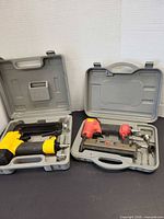 Both staple guns in their respective cases side by side