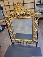 Full view of gilt wall mirror hanging on display grid
