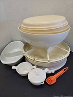 Full group shot of stacked cake carrier components, divided round tray, oval server, sugar bowl, handled bowl and measuring spoons