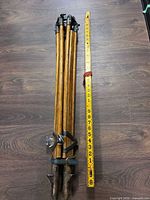Folded wood tripod and yellow measuring rod full view