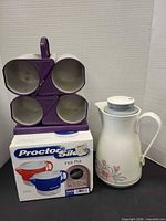 Group shot of Proctor Silex Hot Pot box, floral thermos carafe, Snug Mug carrier with four mugs