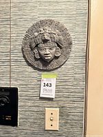 Front view of gray round wall plaque mounted on wall