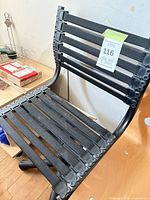 Front angled view of chair showing black bungee cords, graphite frame, casters, and lot tag