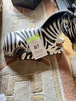 Reclining black and white ceramic zebra figurine on floor