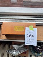 Closed wood box with engraved brass plaque and auction tag visible