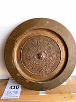 Front view of copper plaque showing Aztec Sun Stone relief and patina
