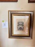 Framed Indigenous mask print hanging on wall showing frame details and artwork