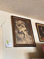 Framed sepia print of romantic classical figures in gilded wood frame hung on wall