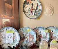 Left section of display showing five plates on stands plus wall-mounted plate
