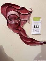 Front view of the sculpted burgundy leather wall mask mounted on wall