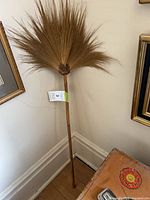 Full view of broom showing fan of palm/coir fibers and wood handle