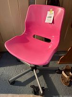Front angled view of pink IKEA office chair showing seat, back cutout, metal base and casters