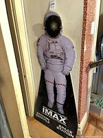 Front view of life-size IMAX astronaut standee leaning against wall