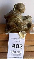 front and side view of green soapstone Inuit figure on wooden surface