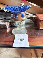 Full view of candle holder showing ruffled rim, wooden collar with cabochons, clear pedestal base