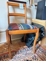 Full view of wood side chair showing ladder back, curved legs, striped fabric seat
