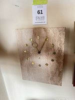 Front view of rectangular beige travertine wall clock with gold markers and hands