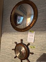 Brass porthole mirror above ship wheel barometer mounted on wall