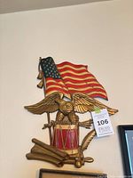 Front view of carved wooden plaque showing eagle, flag, drum and cannons