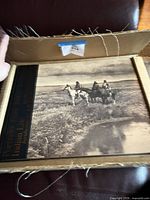 Book inside open cardboard sleeve showing front cover with riders image