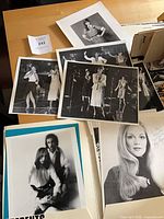 Overview of multiple black-and-white publicity photographs laid out on table, showing several performance and portrait shots of Marilyn Lange