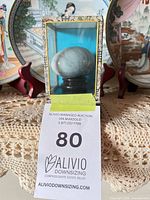 Front view of soapstone egg on wooden stand inside fabric-covered display box