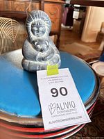Front view of soapstone Inuit figurine holding seal with reference tag visible