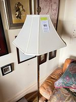 First floor lamp showing brass pole, white square shade, decorative finial