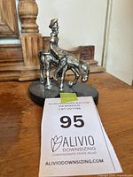 Front view of cast metal figurine with rider on donkey mounted on black stone base