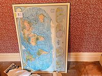 Full view of framed world map print leaning against wall
