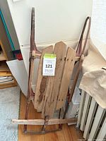 full view of wooden sled showing slat deck, metal runners, steering bar