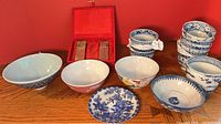 Group shot of all porcelain bowls, cups, plate and plaque case