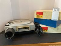 Front view of projector with power cord and boxed slide tray