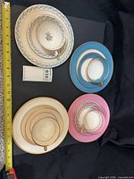 Four stacks each showing cup, saucer and plate with tape for scale