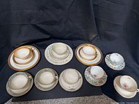 Group view of nine assorted porcelain and bone china teacup, saucer and dessert plate sets