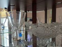 Twist-stem goblet and cut crystal bowls on mirrored shelf