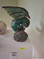 Full view of green dragon figurine on base with measuring tape showing height