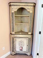 Full front view of closed corner cabinet showing shelves and painted design
