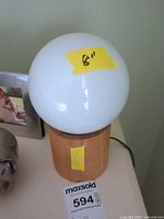 white glass globe lamp on wood base with size tape