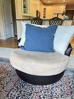 Full view of round two-tone swivel chair with pillows