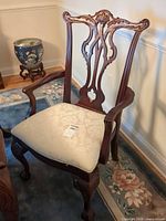 Front view of one armchair showing carved back, arms, seat fabric