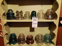 Shelf showing 11 assorted glass insulators in various colours
