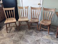 Front view of four spindle-back chairs showing two different designs and overall wear