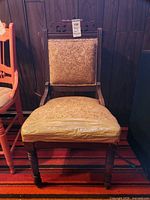 Front view of carved wood upholstered chair showing upholstery and turned legs
