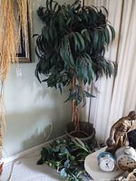 Tall artificial tree in planter next to wall