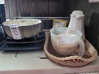 Stacked bakeware, measuring cup, wicker tray and pitcher