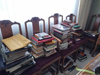 Four chairs stacked with numerous mixed books